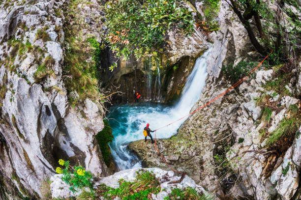 Outdoor pursuite Members of canyoning team communicating by the waterfall while finding their way through the canyon. canyoneering stock pictures, royalty-free photos & images