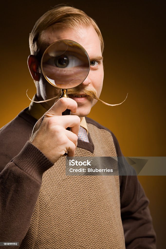 Detective Retro-Styled man with mustache looking through a magnifying glass. Magnifying Glass Stock Photo