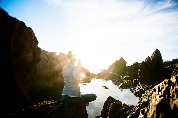 istock Woman meditating on rocks at sunrise 181899200