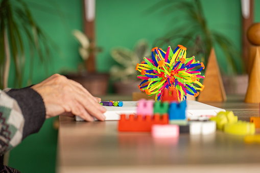 Elderly  man with Alzheimer’s Disease is sitting at the table in is home and uses colorful sensory ball.