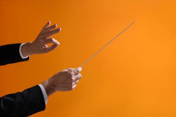 istock Professional conductor with baton on orange background, closeup. Space for text 1818998400