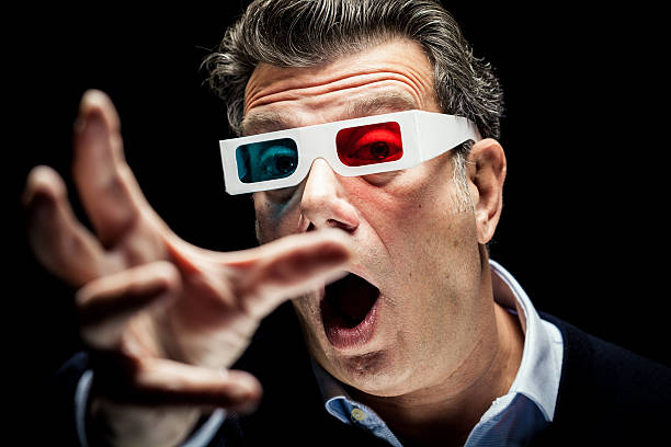A very suprised man tryes to catch objects from the screen with his hand