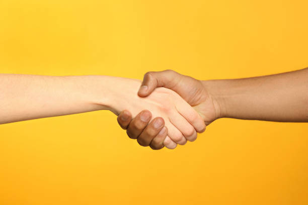 istock International relationships. People shaking hands on orange background, closeup 1818999749