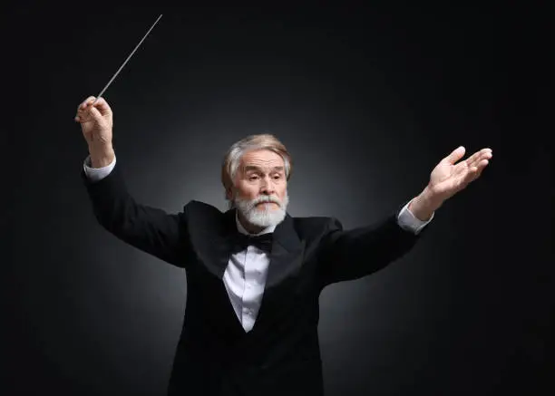 Photo of Professional conductor with baton on black background