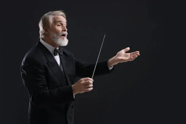 Photo of Professional conductor with baton on black background