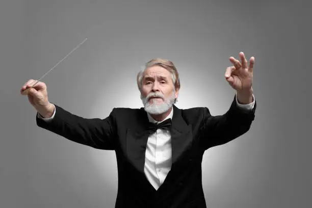 Photo of Professional conductor with baton on grey background