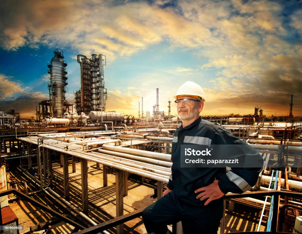 All is under control "Experienced engineer overlooking oil refinery plant in a sunset, dramatic sky colors" Industry Stock Photo