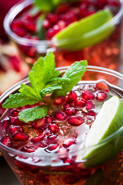 Close up shot of a pink cocktail decorated with a mint leaf.