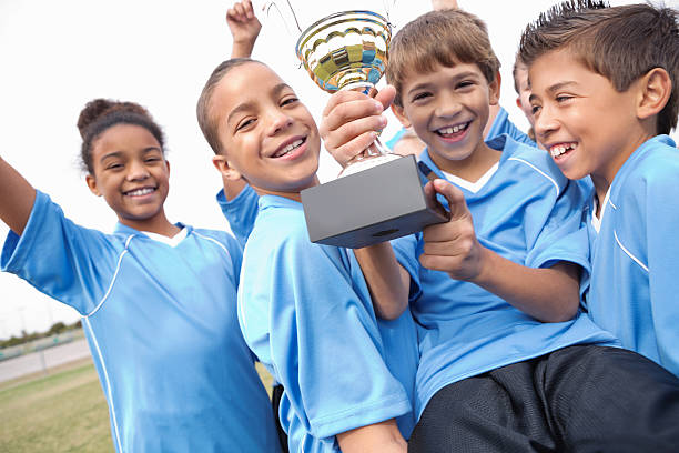 istock Excited kids' soccer team celebrating win with trophy 181901128