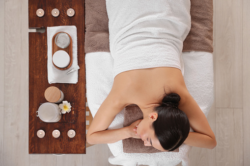 Young woman resting after professional massage in spa salon, top view