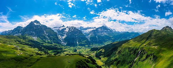 Grindelwald view and summer Swiss Alps mountains panorama landscape, green fields and high peaks in background, Switzerland, Bernese Oberland, Europe.