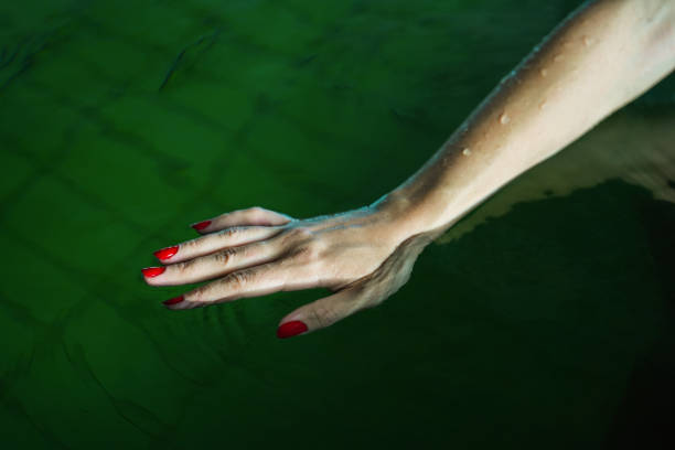 istock hands with red nail polish in hot water pool 1819032701