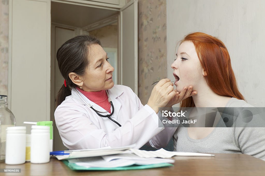 Femmina medico guarda Gola di adolescente - Foto stock royalty-free di Accudire