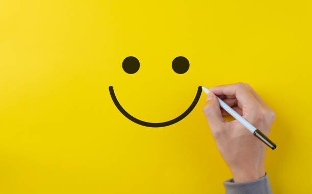 istock Customer review satisfaction feedback survey concept. Hand using pen to draw happy smiling face on yellow background. Service product evaluation business, Positive thinking, Mental health assessment, 1819041839