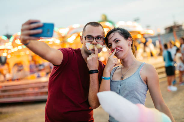 istock Young Couple With Cotton Candy Mustaches Taking Selfies In Amusement Park 1819080501