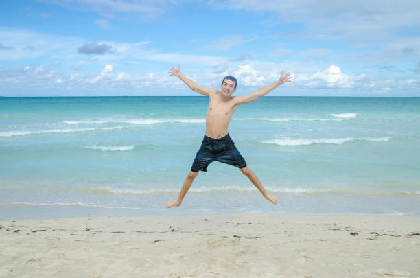 Teenage boy jumping at Varadero beach during day
