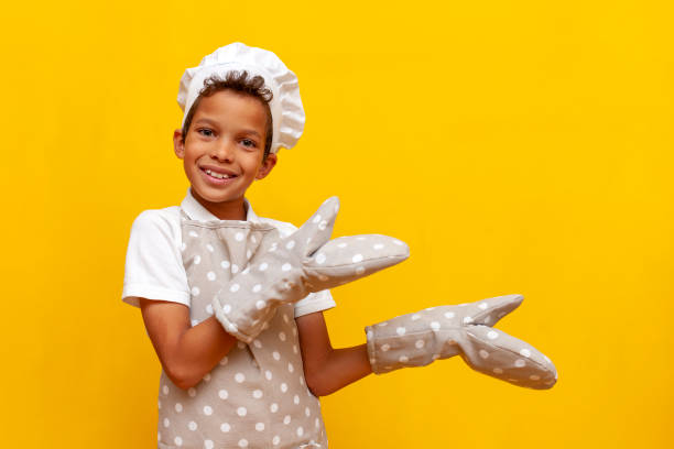 istock boy african american baker in uniform and chef's hat points to the side on yellow isolated background 1819083291