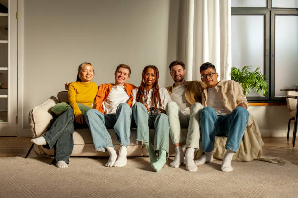 istock multiracial group of young friends sitting on sofa at home hugging and looking at camera 1819083937