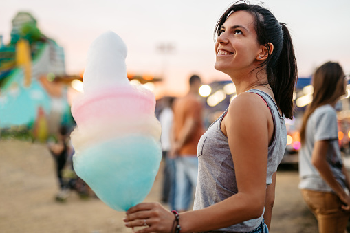 Young woman with cotton candy in an amusement park.