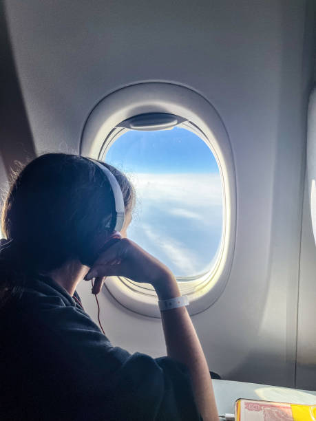 istock Teenage girl looking through airplane window 1819089570