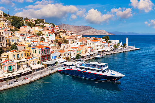 View on Symi (Simi) island harbor port, classical ship yachts, houses on island hills, Aegean Sea bay. Greece islands holidays vacation travel tours from Rhodos island. Symi, Greece,  Dodecanese.