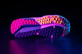 A sole of running shoe isolated on black background in neon coloured lighting