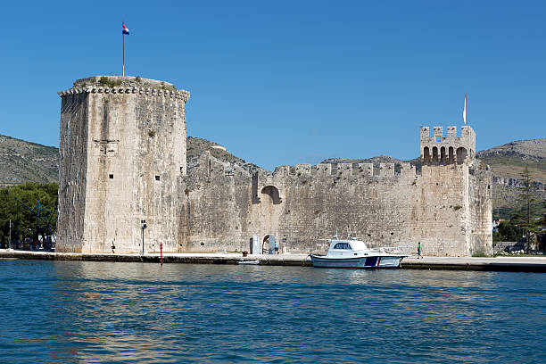 Mature woman wearing sunglasses and looking at town in Trogir, Croatia, Europe.