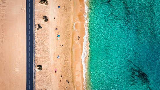 Aerial view of beach with asphalt road in Corralejo Park, Fuerteventura. Beach (Grandes Playas de Corralejo) and road on Fuerteventura, Canary Islands, Spain. Beautiful turquoise water and white sand.