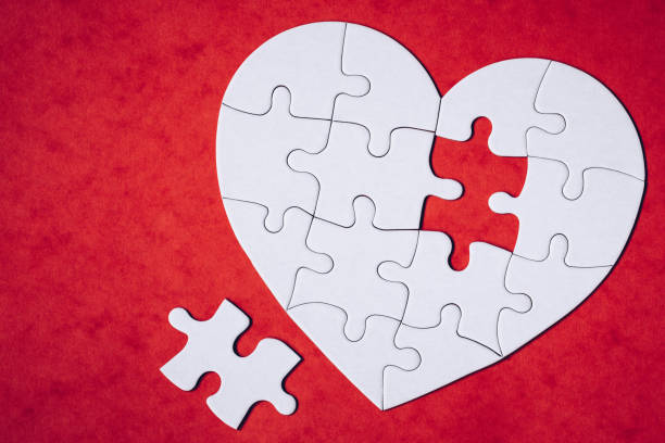 istock Heart-shaped jigsaw puzzle on color background. Puzzle heart on wooden background. A missing piece of the heart puzzle. Heart shape jigsaw puzzle. Puzzles in the shape of a heart. 1819118430