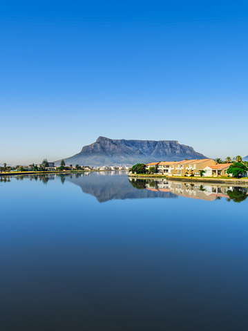 Vertical shot of the table mountain and its reflection in the woodbridge island lagoon during a clear day with blue sky, Cape Town South Africa