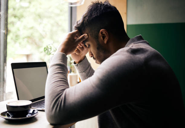 istock Remote work, laptop and man with headache at a cafe with stress, 404 or glitch, problem and screen space. Business, burnout and freelancer at coffee shop with deadline anxiety, mistake or review fail 1819164071
