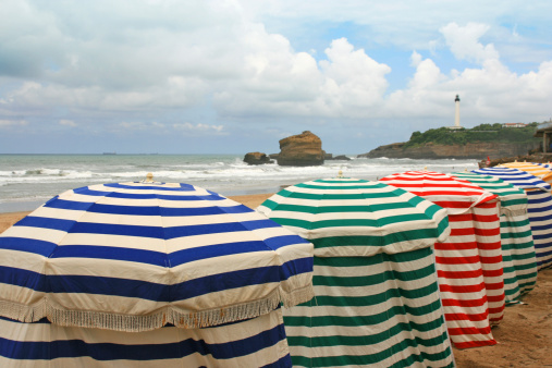 Colored striped beach umbrellas line up along the summer sand in Biarritz, Pays Basque.