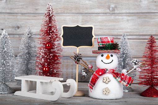 Christmas ornaments, lights and snow on blue surface and wooden background with copy space