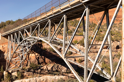 Side View Metal Construction Of Bridge Supports, Infrastructure. Blue Sky And Mountain. Rivets And Braces On Metal Beams. Midgley Bridge, Sedona Arizona, Coconino County. Oak Creek Canyon