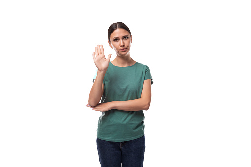 young serious black-haired woman with collected hair is dressed in a basic t-shirt and jeans.