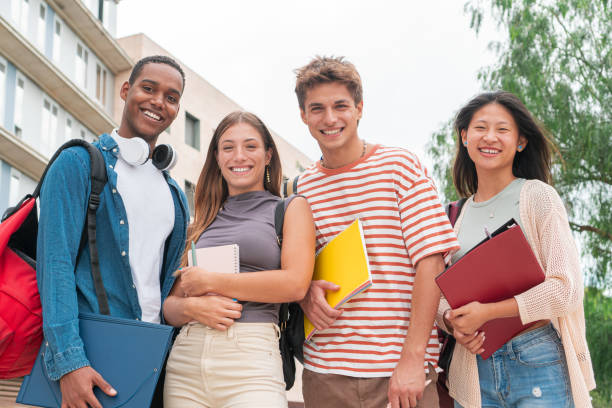istock University students looking at camera and smiling. Multicultural classmates laughing with positive attitude. Joyful young group outside with notebooks and backpack 1819350865