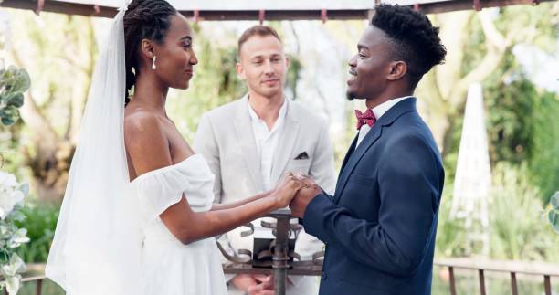 istock Happy black couple, wedding and vows in marriage, commitment or support together at alter. Married African woman and man holding hands for love, trust or speech of bride or groom in outdoor romance 1819369122