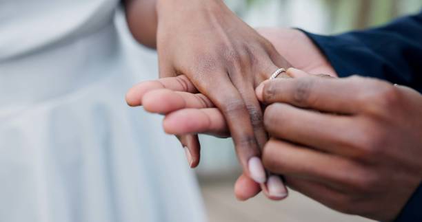 istock Couple, holding hands and ring for marriage, love or wedding in ceremony, commitment or support. Closeup of people getting married, vows or accessory for symbol of bond, relationship or partnership 1819369138