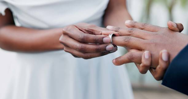 istock Couple, holding hands and ring for marriage, commitment or wedding in ceremony, love or support. Closeup of people getting married, vows or accessory for symbol of bond, relationship or partnership 1819369142