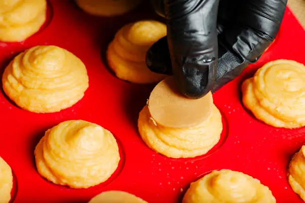 In the kitchen showing the process of placing craquelin on the top of choux pastry prior to baking.