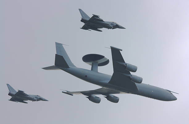 AWACS aircraft with Eurofighter escorts A Boeing E3 Sentry AWACS (Airborne Warning & Control System) or AEW (Airborne Early Warning) aircraft is escorted through a stormy sky by two Eurofighter Typhoons. fighter plane photos stock pictures, royalty-free photos & images