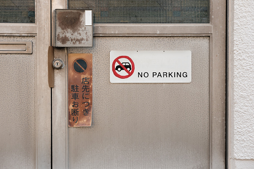An old faded sign on a door telling people not to park there.