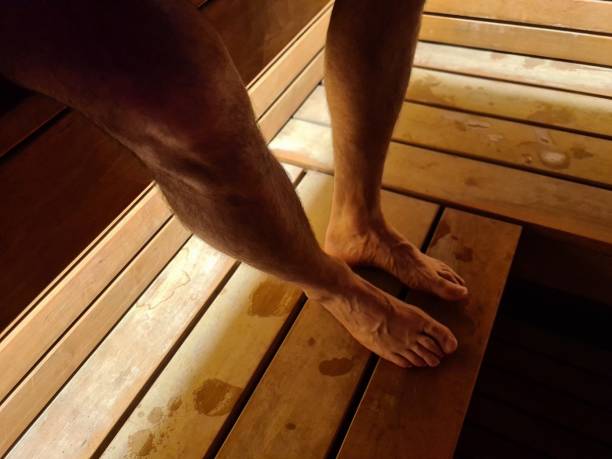Male legs and feet sweat while relaxing in sauna. Wellness treatment for detoxification and strengthening immune system