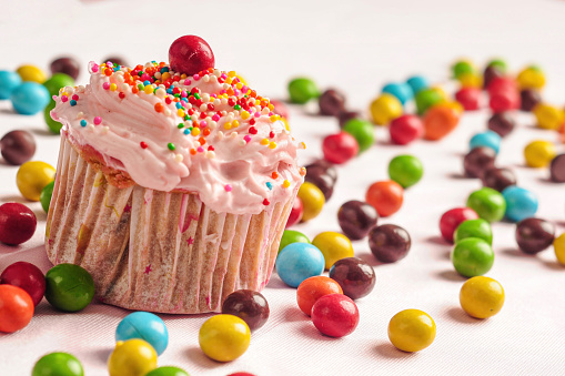 Cupcakes decorated with candy and colorful sprinkles with round candies scattered on the floor