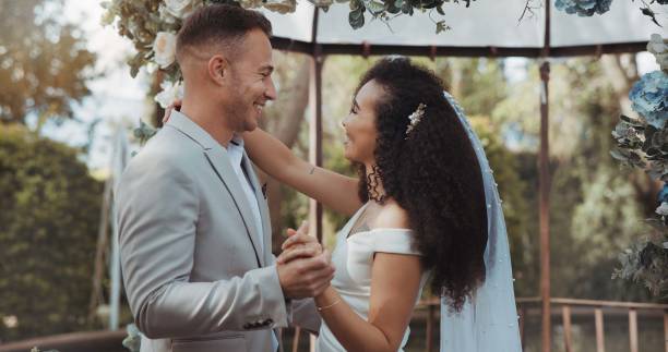 istock Couple, wedding and dancing with touch, smile and commitment in celebration. Interracial marriage, fashion and happy in outdoor, love and romance in conversation, trust and vertical in nature or cute 1819424899