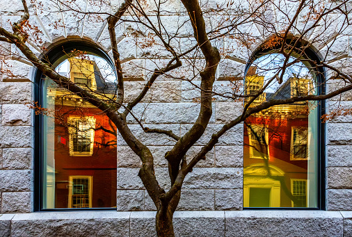 Cambridge, Massachusetts, USA - November 25, 2023: Boylston Hall is a Harvard University classroom and academic office building lecture hall near the southwest corner of Harvard Yard in Cambridge. It was built in 1858 and clad in stone, specifically Rockport granite. Reflections of Wigglesworth Hall seen in the windows.