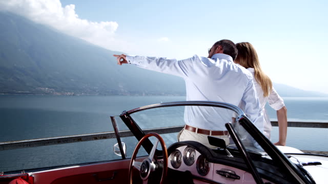 Couple with convertible watching over a lake