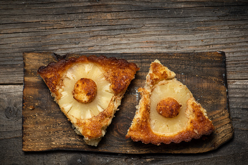 Pieces of sweet pie with pineapple on a wooden background. With copy space