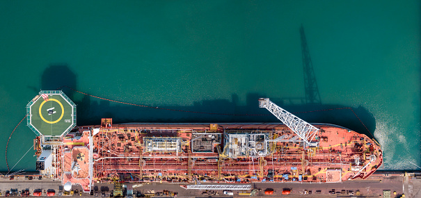 Cargo tanker ship marine vessel docking on the oversea berth mooring platform for petroleum and crude oil industry from top view angle