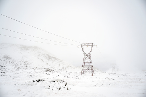 Transmission tower on snow covered mountain in winter in Hveragerði, Iceland